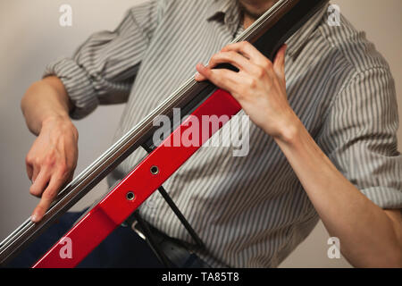 Die Hände eines Mannes spielen Rot moderne elektrische Kontrabass in der musikalischen Studio Stockfoto