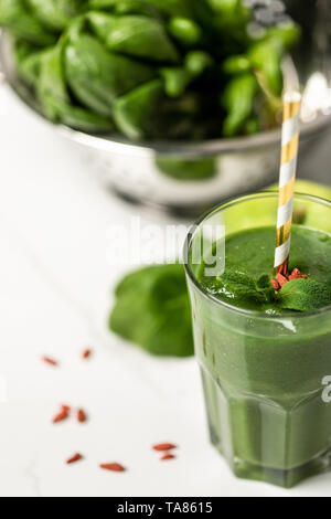 Selektiver Fokus der leckeren Smoothie mit Goji Beeren und Minze im Glas mit Stroh in der Nähe von spinatblätter auf Weiß Stockfoto