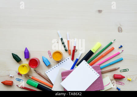 Konzept der Kunst: Komposition mit leerer Hinweis Pads, Marker, Stifte und Farben umgeben sind auf einer hölzernen Hintergrund, mit Platz für Text Stockfoto