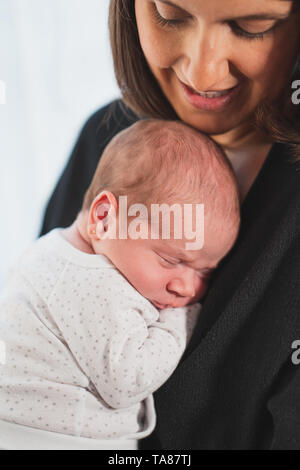 Neue Mutter ihr cute adorable Neugeborene schlafen auf seinem Schoß. Baby bringt Ruhe und Frieden. Familie, neue Leben, Kindheit, Anfang Konzept. Stockfoto