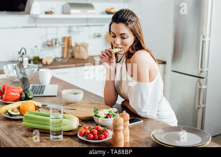 Nachdenkliches Mädchen am Tisch sitzen und essen Salat in der Küche Stockfoto