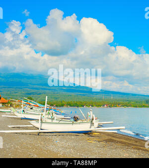 Sonnenschein Wetter am Strand mit traditionellen Fischerbooten, Agung Vulkan in Wolken im Hintergrund, Bali, Indonesien Stockfoto
