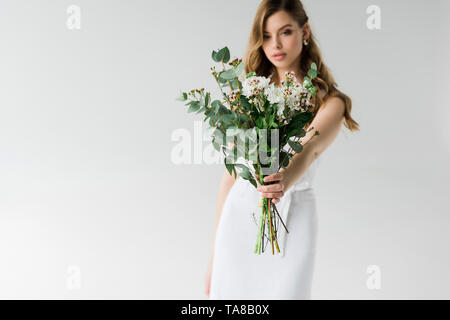 Selektiver Fokus von Blumen in der Hand von attraktiven Mädchen auf weißem Stockfoto