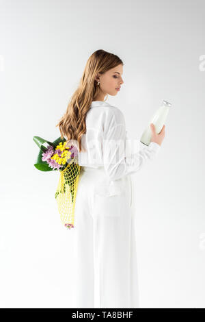 Attraktive Frau mit Flasche Milch und Gelb string Beutel mit Wildblumen auf Weiß Stockfoto