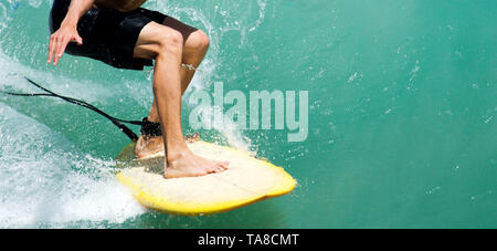 Die untere Hälfte einer männlichen Surfer auf einer Welle in klarem Wasser Stockfoto