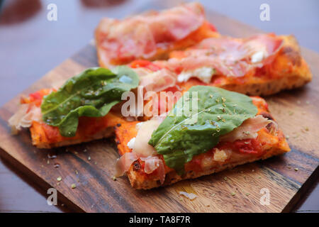 Pizza mit Parmaschinken salat rucola und Parmesan auf dunklem Hintergrund. Italienisches Essen Stockfoto