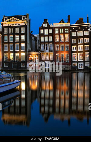 Damrak Grachtenhäuser bei Nacht - Amsterdam Canal House Reflexion tanzen Häuser von Damrak Reflexionen in der Nacht - reflektierende Häuser canal Damrak. Stockfoto