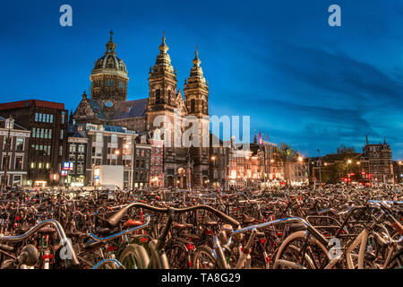 Amsterdam Fahrräder - Fahrräder in Amsterdam bei Nacht mit der Kirche des Heiligen Nikolaus im Hintergrund - Hunderte von abgestellte Fahrräder - biketown Amsterdam Stockfoto