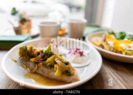 Gegrillter Lachs oder Forelle mit Brokkoli champignons Soße und Gemüse. Drinnen Nahaufnahme. Tisch im Restaurant in der Nähe der Fenster Stockfoto