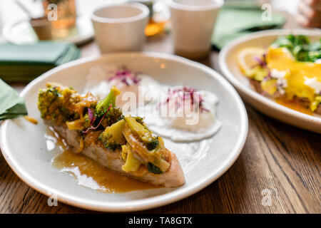 Gegrillter Lachs oder Forelle mit Brokkoli champignons Soße und Gemüse. Drinnen Nahaufnahme. Tisch im Restaurant in der Nähe der Fenster Stockfoto