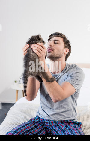 Glückliche Menschen auf Betten zu Hause sitzen und halten adorable Waschbär. Stockfoto