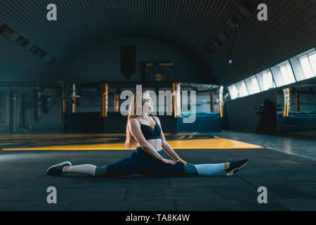 Stretching gymnast Mädchen tun Vertical Split, Garn. Seitenansicht der attraktive junge Frau tun core Übung bei crossfit Fitnessraum Stockfoto