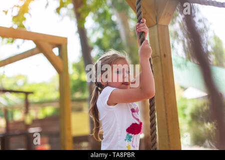 Kind im Wald Abenteuer Park. Kinder klettern auf hohem Seil Trail Stockfoto