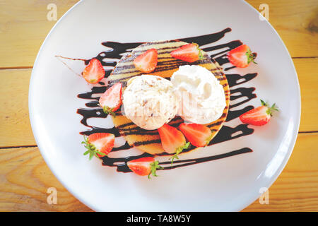 Erdbeere Pfannkuchen Chocolate Chip Eis/Dessert frische Erdbeeren Obst auf Pfannkuchen mit Vanilleeis und Sahne gießen c Stockfoto