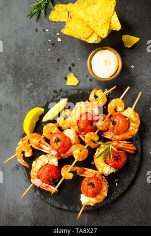 Köstliche gegrillte Garnelen mit Spice, Zitrone und Soße auf einer Schiefer Board serviert mit Nachos Chips serviert. Fisch und Meeresfrüchte. Ansicht von oben flach Hintergrund. Kostenlose sp Stockfoto