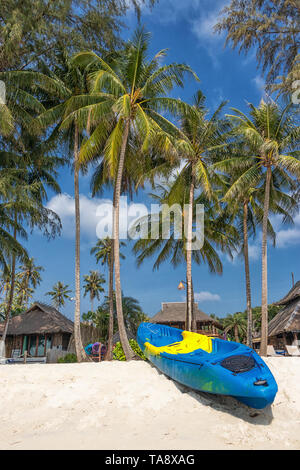 Sommer Urlaub mit Aktivität am tropischen Strand Konzept. Farbenfrohe Kajak Boot auf weißen Sandstrand mit Kokosnuss Palmen im Hintergrund. Stockfoto