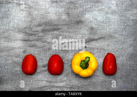 Gemüse auf einem grauen Hintergrund von Flachs. Tomaten, gelbe Paprika, Gurke, Zitrone, Meerrettich Stockfoto