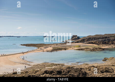 Touristen zu Fuß auf Causeway zu Grand Bé Insel mit Fort du Petit Bé im Hintergrund, Saint Malo, Bretagne, Frankreich Stockfoto