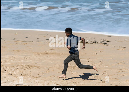 Ein junger Teenager begeistert läuft an einem sonnigen Tag an Fistral Beach in Newquay in Cornwall. Stockfoto