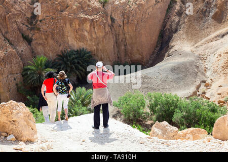 TOZEUR, Tunis - ca. Mai, 2012: Touristen fotografieren die Inschrift mit den Worten: Bienvenue Chebika, willkommen. Zeichen ist am Hang mit Steinen und pebb verlegt Stockfoto