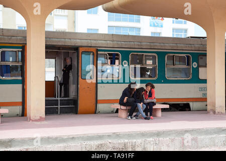 Ein Elektroauto mit offenen Türen am Bahnhof in Monastir. Die Mädchen sitzen auf der Bank. Tunesien, Afrika Stockfoto