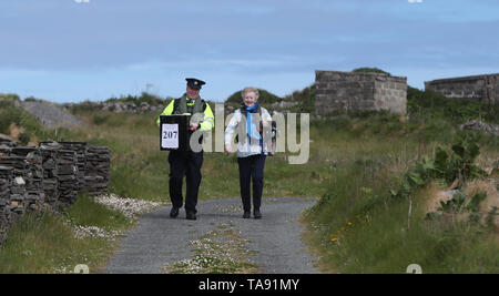 Vorsitzende Carmel McBride und Gardasee Adrian McGettigan einer Wahlurne zum Wahllokal tragen auf der Insel Inishbofin. Die Wähler auf dem entfernten Insel vor der Küste von Donegal waren unter den ersten, die ihren Stimmzettel in den lokalen und europäischen Wahlen, einen Tag vor dem Rest des Landes zu werfen. Stockfoto