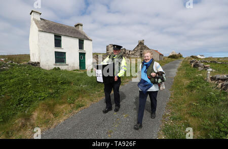 Vorsitzende Carmel McBride und Gardasee Adrian McGettigan einer Wahlurne zum Wahllokal tragen auf der Insel Inishbofin. Die Wähler auf dem entfernten Insel vor der Küste von Donegal waren unter den ersten, die ihren Stimmzettel in den lokalen und europäischen Wahlen zu werfen, einen Tag vor dem Rest des Landes. Stockfoto