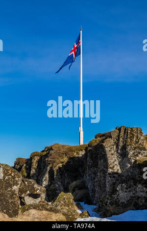 Isländischer Flagge an der Schlucht Almannagjá, der erste Parlament der Welt und ein wichtiger Teil der isländischen Identität, in Þingvellir-Nationalpark, Eis Stockfoto
