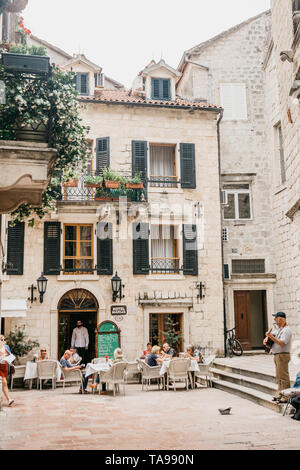 Montenegro, Kotor, 23. Mai 2019: die Menschen essen und Erholung in einer Street Cafe. In der Nähe einer Straße Musiker spielt auf der Gitarre. Stockfoto