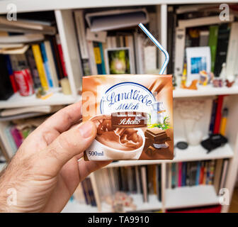 Paris, Frankreich - Mar 16, 2019: der Mensch hand Schokolade Landliebe Milch mit plastikstrohhalm in Deutschland gegen Wohnzimmer Hintergrund Stockfoto