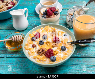 Schüssel mit Haferflocken mit Himbeeren und Blaubeeren auf einem blauen Holztisch. Stockfoto