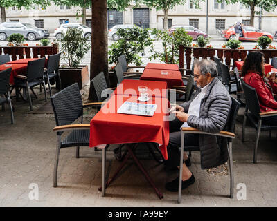 Straßburg, Frankreich - 2. Mai 2018: erwachsener Mann mit Bart mit Smartphone im Cafe Terrasse im Freien lesen Le Figaro und trinken Kaffee Stockfoto