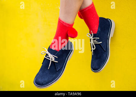 Blau Wildleder Stiefel mit roten Socken gegen eine gelbe Wand. Schrullig und hellen Fashion Concept Stockfoto