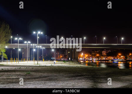 Spielplatz am Strand. Brücke über den Fluss und die Nacht Stadt auf dem Hintergrund Stockfoto