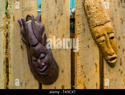 Traditionelle afrikanische Holzmasken hängend an einem Holzzaun Stockfoto