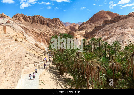 TOZEUR, TUNESIEN - ca. Mai, 2012: Besucher gehen in Chebika (Qasr el-Shams) Berg Oase am Fuße des Djebel el Negueb in westlichen Tunesien. Es ist fam Stockfoto