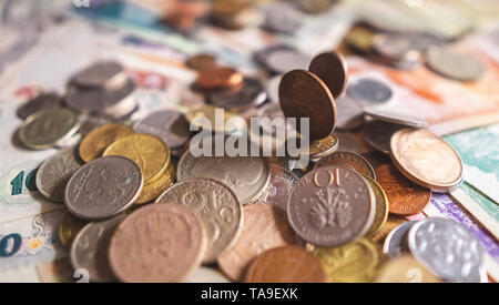 Blick von oben auf die verschiedenen Münzen verteilt auf dem Tisch. Eine Menge Münzen aus verschiedenen Ländern im Stapel. Stockfoto