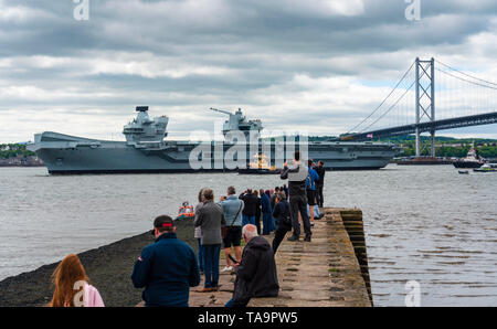 North Queensferry, Schottland, Großbritannien. 23 Mai, 2019. Flugzeugträger HMS Queen Elizabeth Segel von Rosyth in den Fluss Forth nach einem Besuch in ihrem Heimathafen für eine einbauen. Kehrt sie zu Meer für Westlant 19 Bereitstellung und ausgelegt auf den Betrieb ihrer F-35 Kampfflugzeuge zu konzentrieren. Abgebildet; die Menschen versammelten sich in North Queensferry Pier zu sehen der Träger den Fluss Forth fahren. Credit: Iain Masterton/Alamy leben Nachrichten Stockfoto