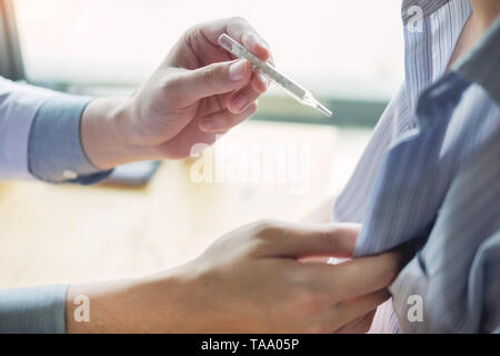 Hand eines Arztes mit Stethoskop. Temperatur, Fieber, Grippe oder Diagnose- und kranke Patienten, die im Krankenhaus Stockfoto
