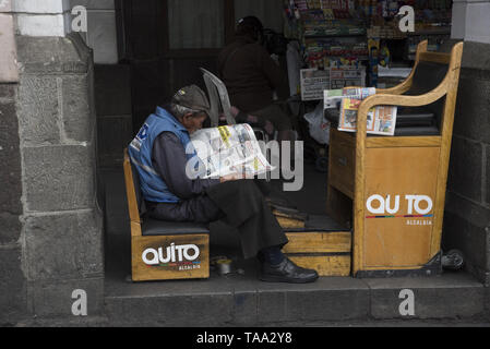 Shoeshiner warten auf Kunden und lesen Zeitung in den Arkaden der Stadt Quito an der Unabhängigkeit in Quito in Ecuador. Stockfoto