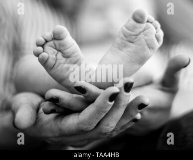 Flache Nahaufnahmen der Hände der Mutter Füße Ihres Babys Holding Stockfoto
