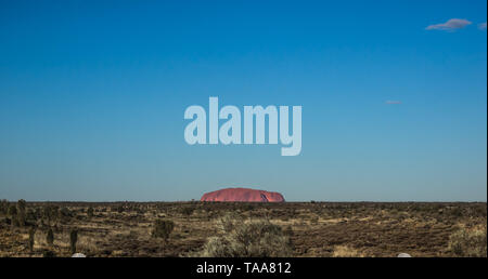 Wahrzeichen Australiens Uluru/Ayers Rock wie aus der Ferne, über der Wüste im roten Zentrum Australiens gesehen Stockfoto