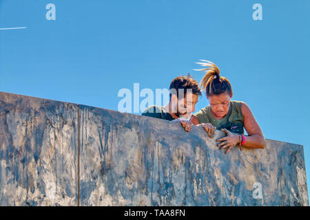 San Fernando, Cadiz, Spanien - 16. März 2019: Unbekannter amateur Athleten, die eine große Anstrengung einen schlammigen Holzwand zu überwinden Stockfoto