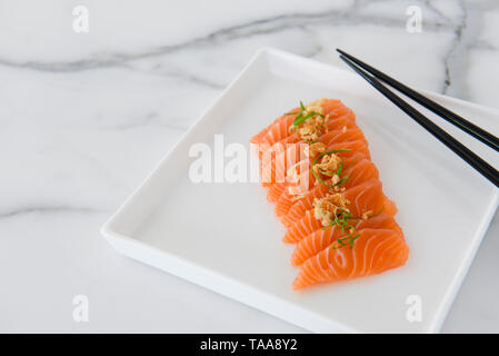 Frisch geschnittenen Lachs sashimi auf weiße Platte mit Stäbchen, flach Stockfoto