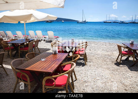 Stühle aus Holz mit Tischen am Strand am Meer Restaurant in Bodrum, Türkei Stockfoto