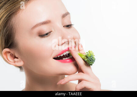 Attraktive und glückliche Frau Grün essen reif Brokkoli isoliert auf weißem Stockfoto
