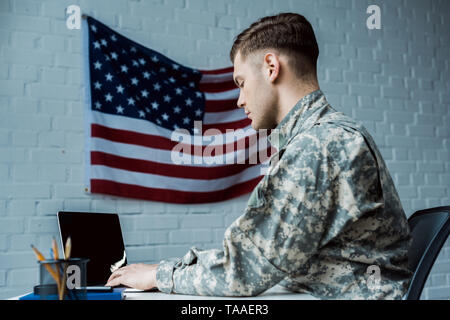 Low Angle View von stattlicher Soldat mit Laptop mit leerer Bildschirm Stockfoto