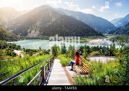 Touristische Frau mit Hut genießen Sie einen wunderschönen Blick auf den See in den Bergen in Kasachstan Stockfoto