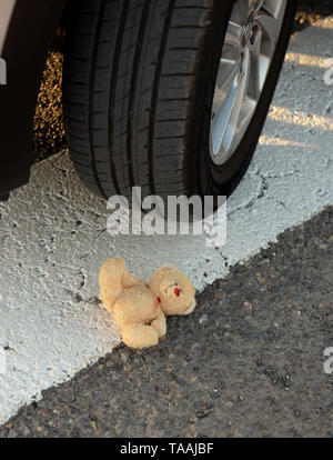 Plüschtier Bär im Blut unter dem Auto Räder. Stockfoto