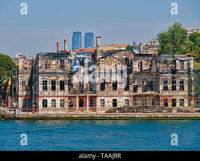 Bosporus, Blick vom Kreuzfahrtschiff. Alte traditionelle beschädigte Gebäude aus Holz mit strukturelle Unterstützung und TAT twin towers im Hintergrund. Stockfoto